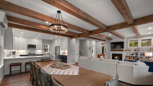 Una cocina amplia con vigas de madera, un comedor con una mesa y sillas de madera, y un espacio de sala de estar con chimenea y asientos.