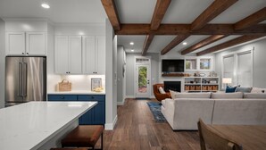 Una cocina moderna con armarios blancos, un refrigerador de acero inoxidable y techo de madera.
