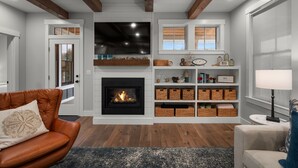 Una sala de estar con chimenea, televisor y estanterías empotradas con cestas.
