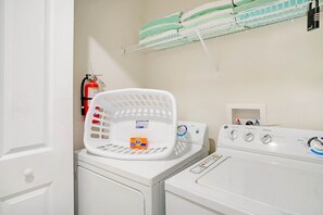 A laundry area with a washing machine, a drying rack, and a fire extinguisher.