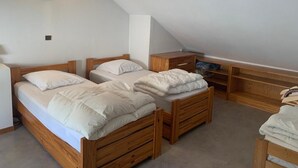 A bedroom with two wooden beds, a small desk, and a slanted ceiling. - 200m from ski lifts, 7th floor, view mountain, balcony, tv, ski locker, 69m², Brides Les Bains (Brides-les-Bains)