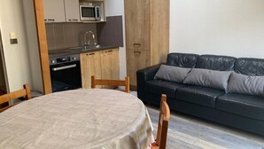 A compact living space with a dining table, a sofa, a kitchen area with a microwave, and wooden cabinets. - 200m from ski lifts, 7th floor, view mountain, balcony, tv, ski locker, 69m², Brides Les Bains (Brides-les-Bains)