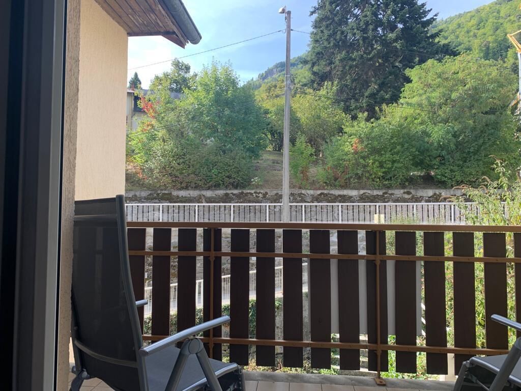 A balcony with a view of a stone wall and greenery.
