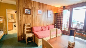 Una stanza accogliente con parete in legno, un letto con biancheria rossa, un tavolo in legno e una sedia.
