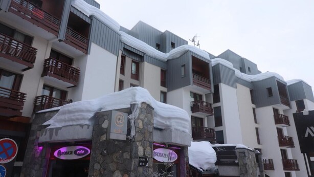 Un hotel a più piani con balconi, pilastri in pietra e indicazioni per una pista di curling.