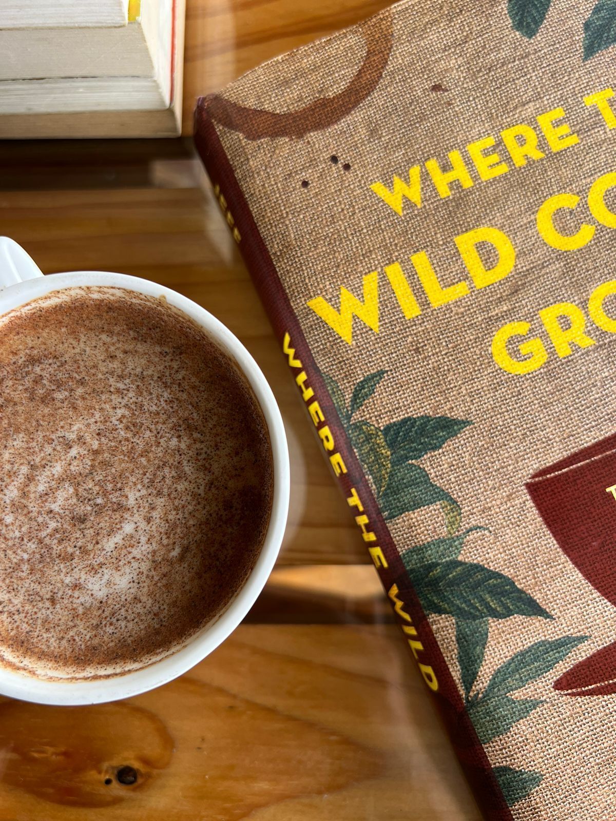 A cup of coffee on a table next to a book titled "Where Wild Cows Go".