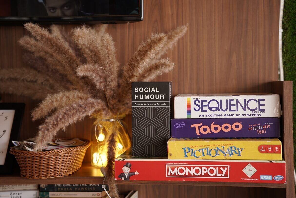 A stack of board games including Monopoly, Sequence, Taboo, Pictionary, and Social Humour.