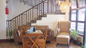 A living area with a sofa, armchair, wooden table, and staircase. - The Living Roof (Shillong)