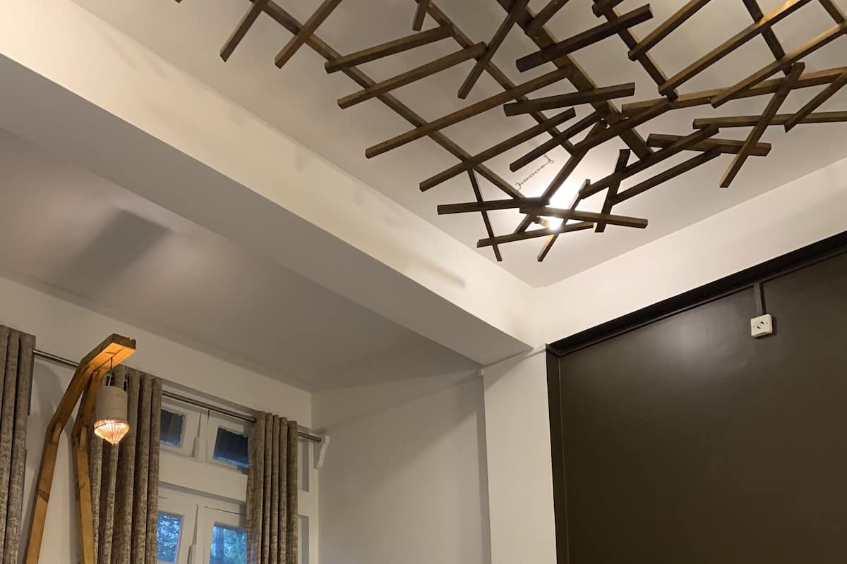 A bedroom with a wooden bed, a ladder, a window with curtains, and a dark wall.