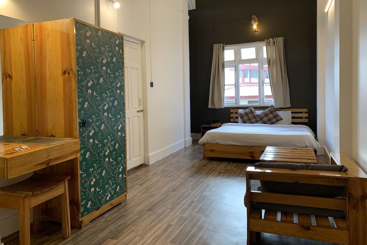 A bedroom with a bed, wooden furniture, a wardrobe, and a window with curtains.