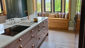 Una cucina moderna con una grande isola, pensili integrati e vista panoramica attraverso ampie finestre.