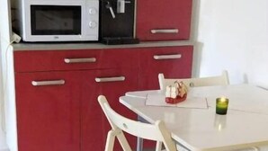 Una cucina compatta con un forno a microonde, una cassaforte nera e un'area pranzo con tavolo e sedie.