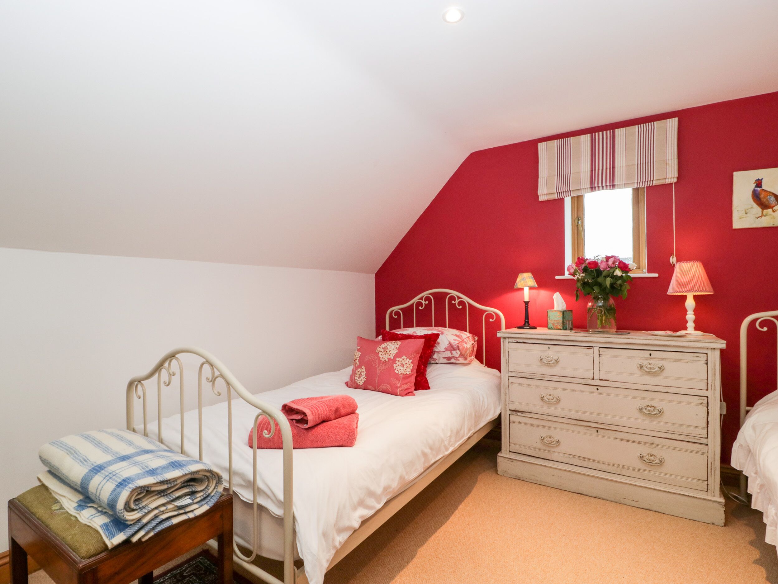 Een slaapkamer met een enkel bed, een nachtkastje, een dressoir en een raam met gordijnen.