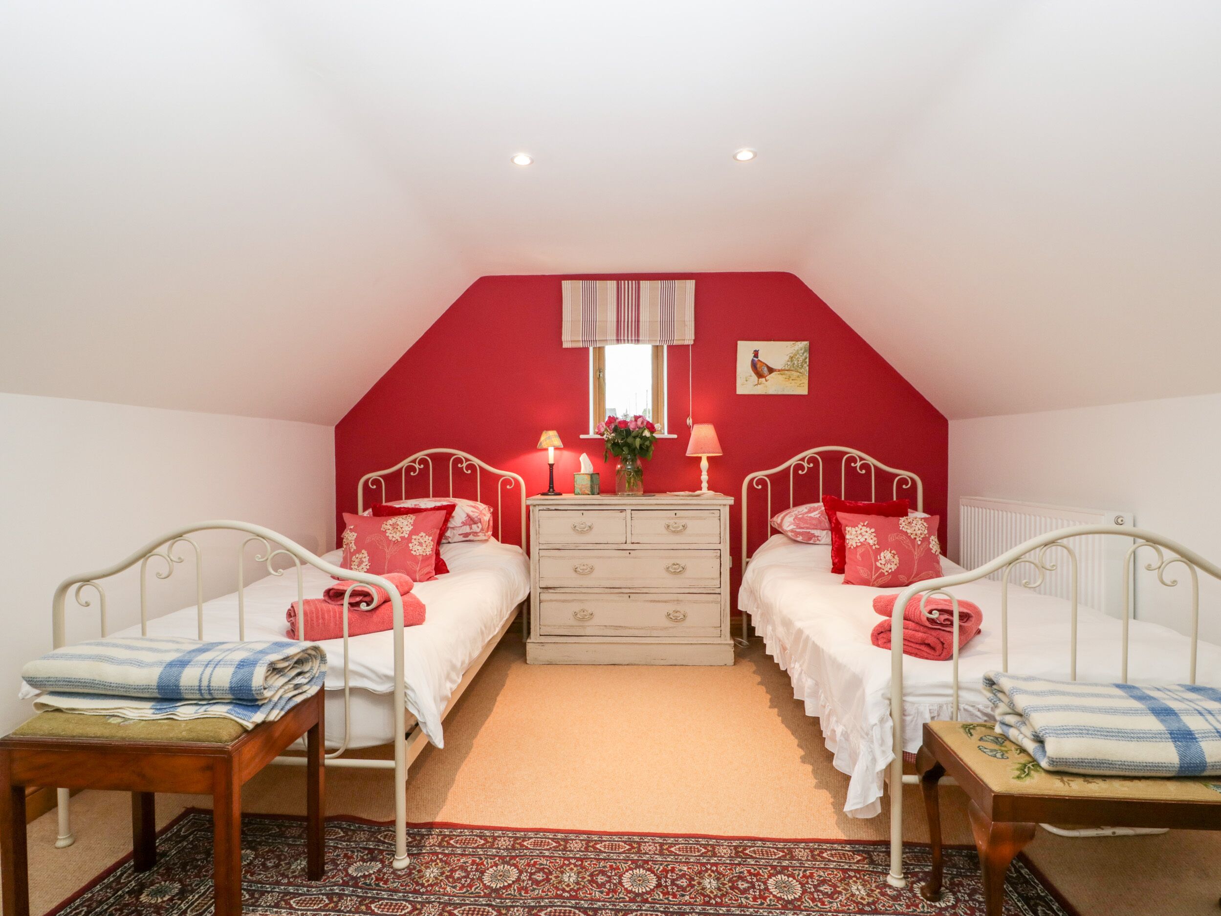 A bedroom with two beds, a dresser, a window with curtains, and a rug.