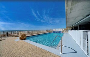 A pool area with a clear view of the ocean, a lifeguard stand, and a covered section.