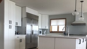 A modern kitchen with white cabinets, stainless steel appliances, and a wooden floor. - Pigeon Lake Luxury close to town of Bobcaygeon (Kawartha Lakes)
