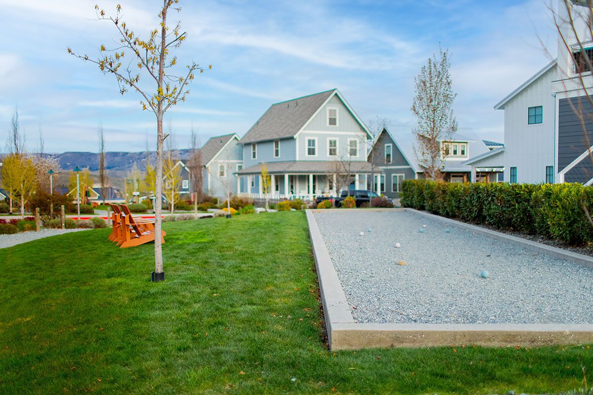 A residential area with houses, a lawn, and a gravel path.