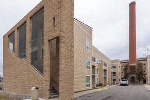 Un immeuble à plusieurs étages, doté d’une façade en briques, de grandes fenêtres et d’une haute cheminée.