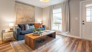 Uma sala de estar com sofá, mesa de centro e um quadro na parede.