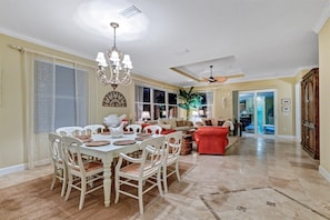 A spacious living room with a dining area, a red sofa, and a ceiling fan.