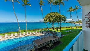 Une vue sur la piscine, avec une vue dégagée sur l’océan, les palmiers et une pelouse bien entretenue.