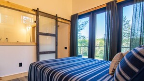 A bedroom with a bed, a sliding door, and a view of the outdoors. - Legends Lane A - Hosted by The Chalets (Logan)