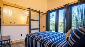 A bedroom with a bed, a desk, and a window with curtains. - Legends Lane B - Hosted by The Chalets (Logan)