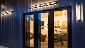 Un bâtiment moderne avec une façade élégante, de grandes portes vitrées donnant sur un intérieur comprenant une cuisine, un coin repas et un espace de vie.