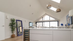 A modern kitchen with a central island, a large window, and a skylight. - 5 Longshore (Newquay)