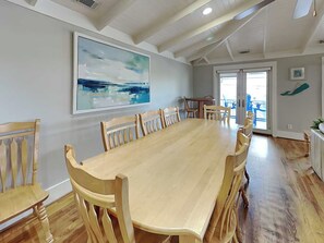 Ein Essbereich mit einem langen Holztisch und Stühlen, einem großen abstrakten Gemälde an der Wand und Blick durch eine Glastür.