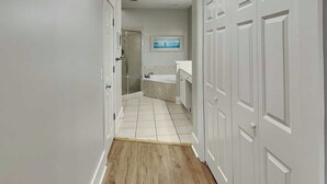 A hallway with a wooden floor, white walls, and a shower area with a glass door. - Partial beach view home w. shared pool + private elevator. (Tybee Island)