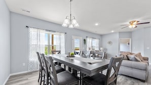 A dining area with a wooden table and chairs, a ceiling fan, and a view of the outdoors. - Walk In Level, Family Friendly, Relaxing New Condo in Stonebridge Resort. (Branson West)