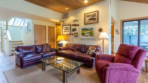 A living room with leather sofas, a glass coffee table, and framed artwork on the walls. - MELA02 - Spacious Home, Hot Tub, Sauna, Sharc Passes, Dog Friendly (Sunriver)