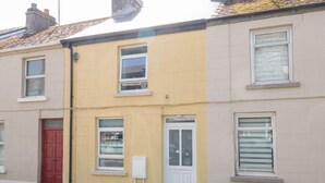 A row of terraced houses with distinct yellow and beige facades, white doors, and windows.
