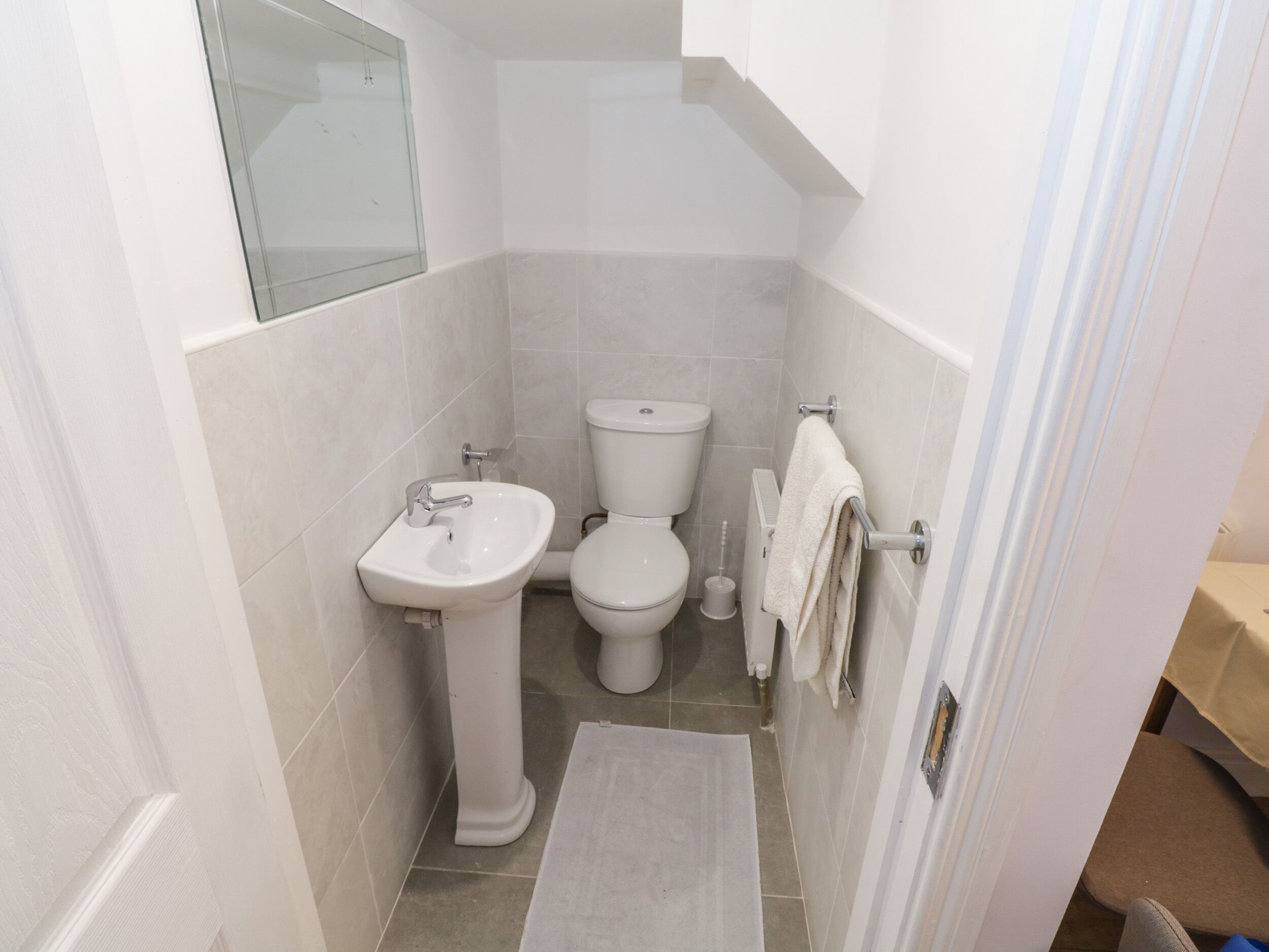 Une petite salle de bain propre, équipée d’un lavabo, de toilettes et d’un porte-serviettes.