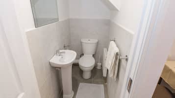 Une petite salle de bain propre, équipée d’un lavabo, de toilettes et d’un porte-serviettes.