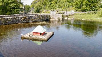 A small wooden dock with a red and white structure, surrounded by calm water and greenery.