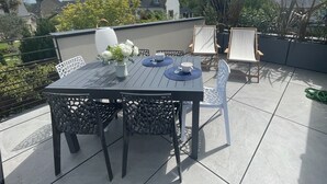 A rooftop terrace with a table set for two, surrounded by chairs, and a potted plant. - Maison du Rocher Plat - Vue Mer - Proche Plage - 4 (Saint-Jacut-de-la-Mer)