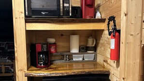 A compact kitchen with a microwave, coffee maker, and a small refrigerator.