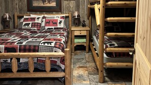 A rustic bedroom with a wooden bed, a bunk bed, and a ceiling light fixture.