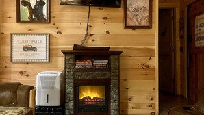 A cozy room with a fireplace, a mounted television, and framed artwork on the walls.
