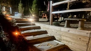 A wooden staircase leading up to a wooden deck area with a fire pit at the base.