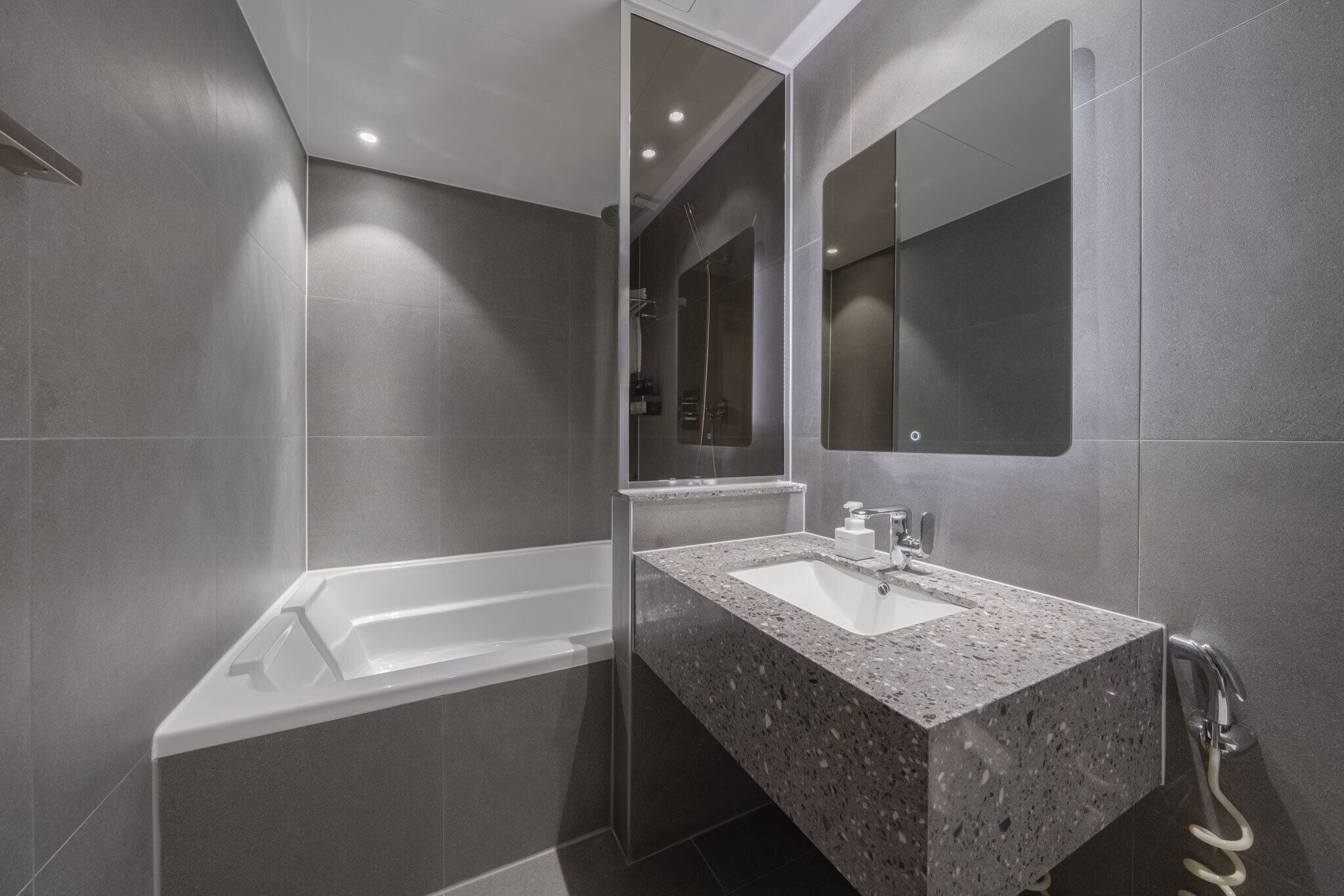 Un baño moderno con una bañera independiente, un lavabo de granito y un espejo grande.
