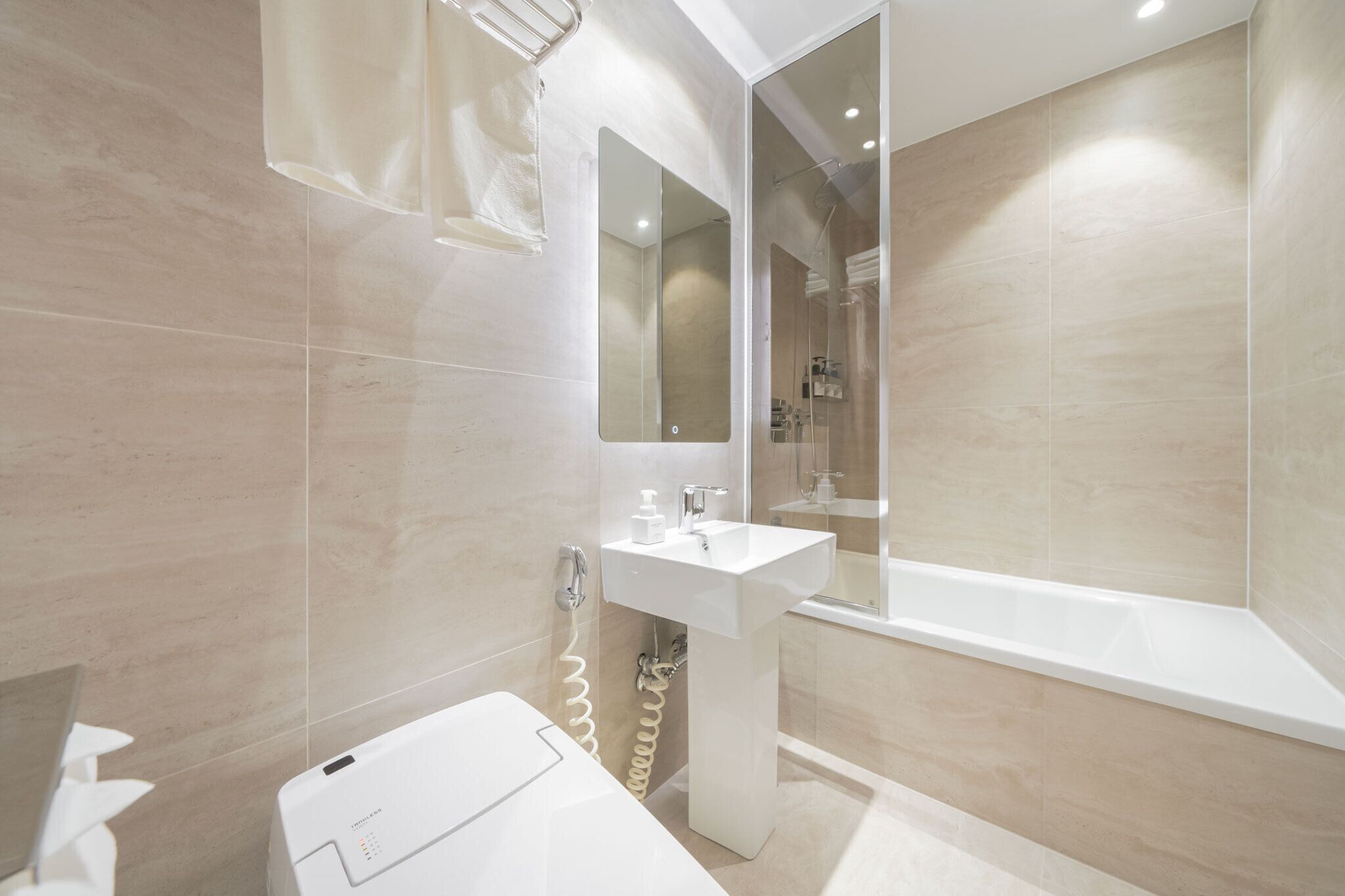 A modern bathroom with a white sink, a mirror, and a bathtub.