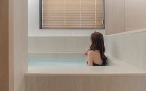 A person sitting in a bathtub with a window above. - Hound Hotel Sungshin Women's University Branch (Seoul)