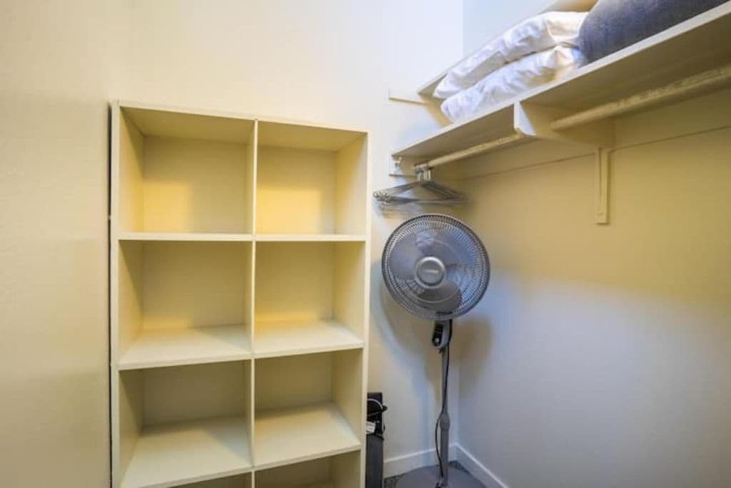 Una habitación con estantería empotrada y un ventilador de pie.