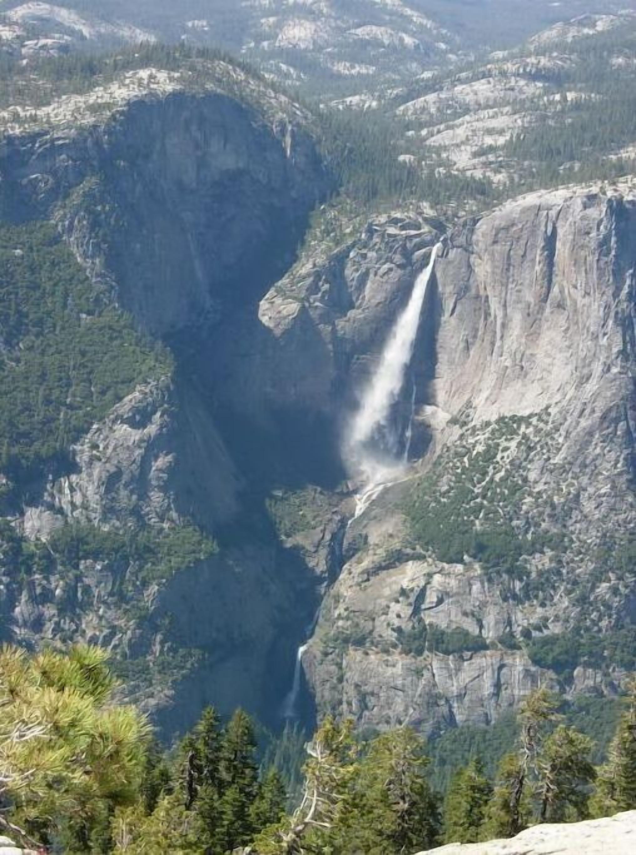A waterfall cascading down a steep cliff surrounded by dense forest.