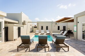 A pool area with lounge chairs, a small pool, and a covered seating area. - Emerald 2BR APT -#E2 in Noord-Sleeps 4 (Noord)