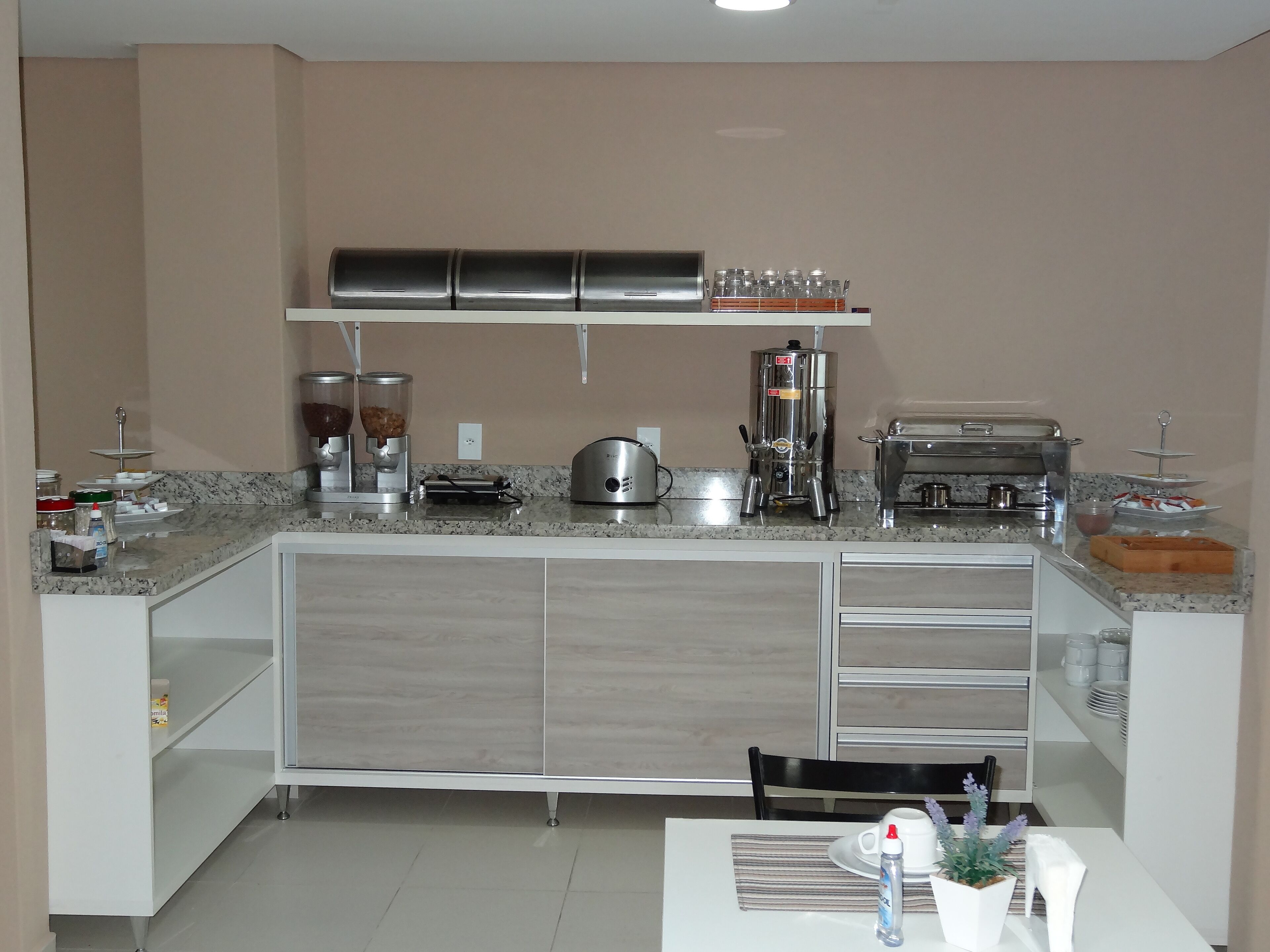 A modern kitchen with a granite countertop, stainless steel appliances, and a white cabinet with drawers.