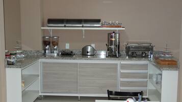 A modern kitchen with a granite countertop, stainless steel appliances, and a white cabinet with drawers.